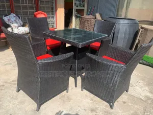 Black Rattan Outdoor Dining Set With a Glass-Top Table Red Cushions.