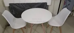 White Round Table and Two White Padded Chairs With Wooden Legs.