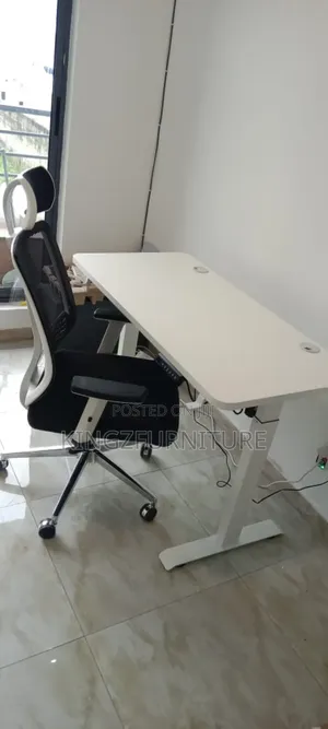 White Electric Standing Desk With an Ergonomic Mesh Office Chair.